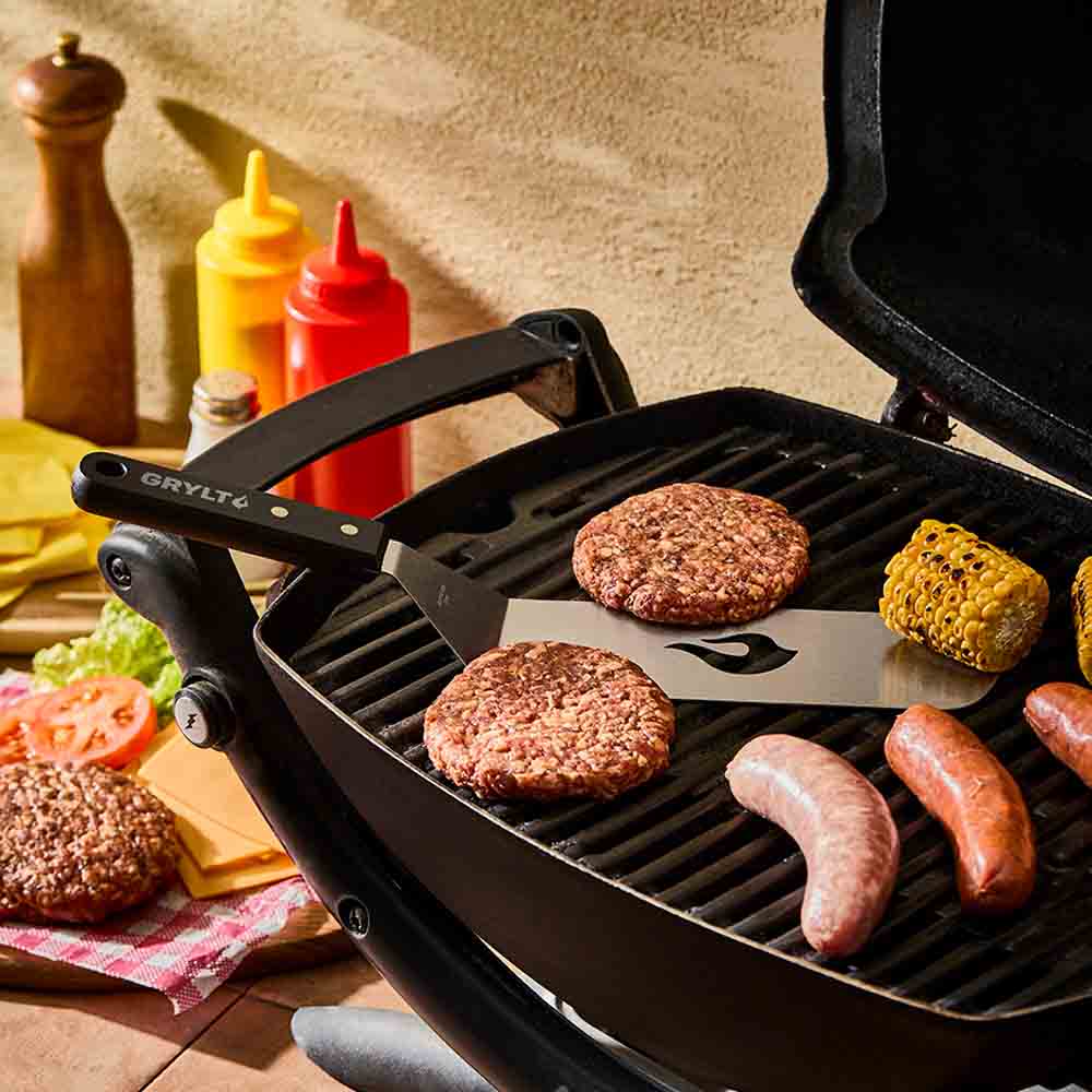 slotted spatula on the BBQ with burgers, corn and sausages- Robins Kitchen