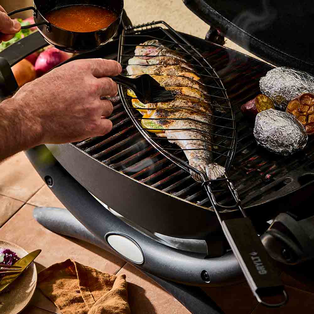 man basting sauce onto a fish on the BBQ - Robins Kitchen