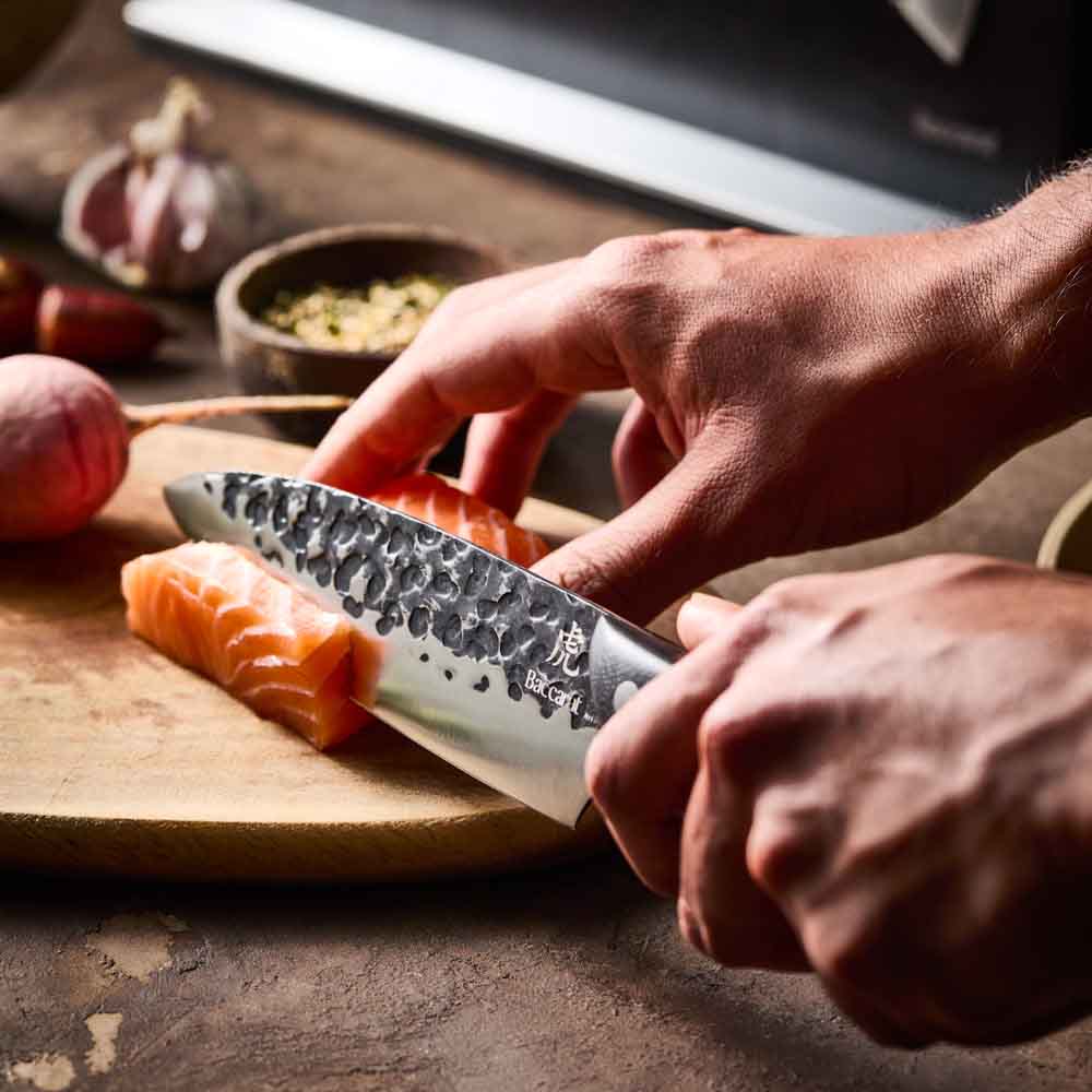 Man slicing salmon with Baccarat KUROI KIBA 7 Piece Knife Block at Robins Kitchen