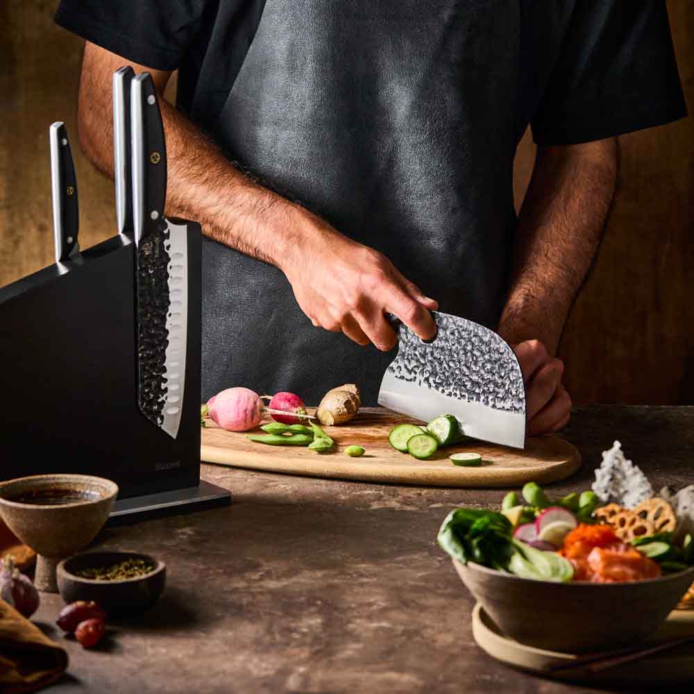 Man slicing cucumber with Baccarat KUROI KIBA 7 Piece Knife Block at Robins Kitchen