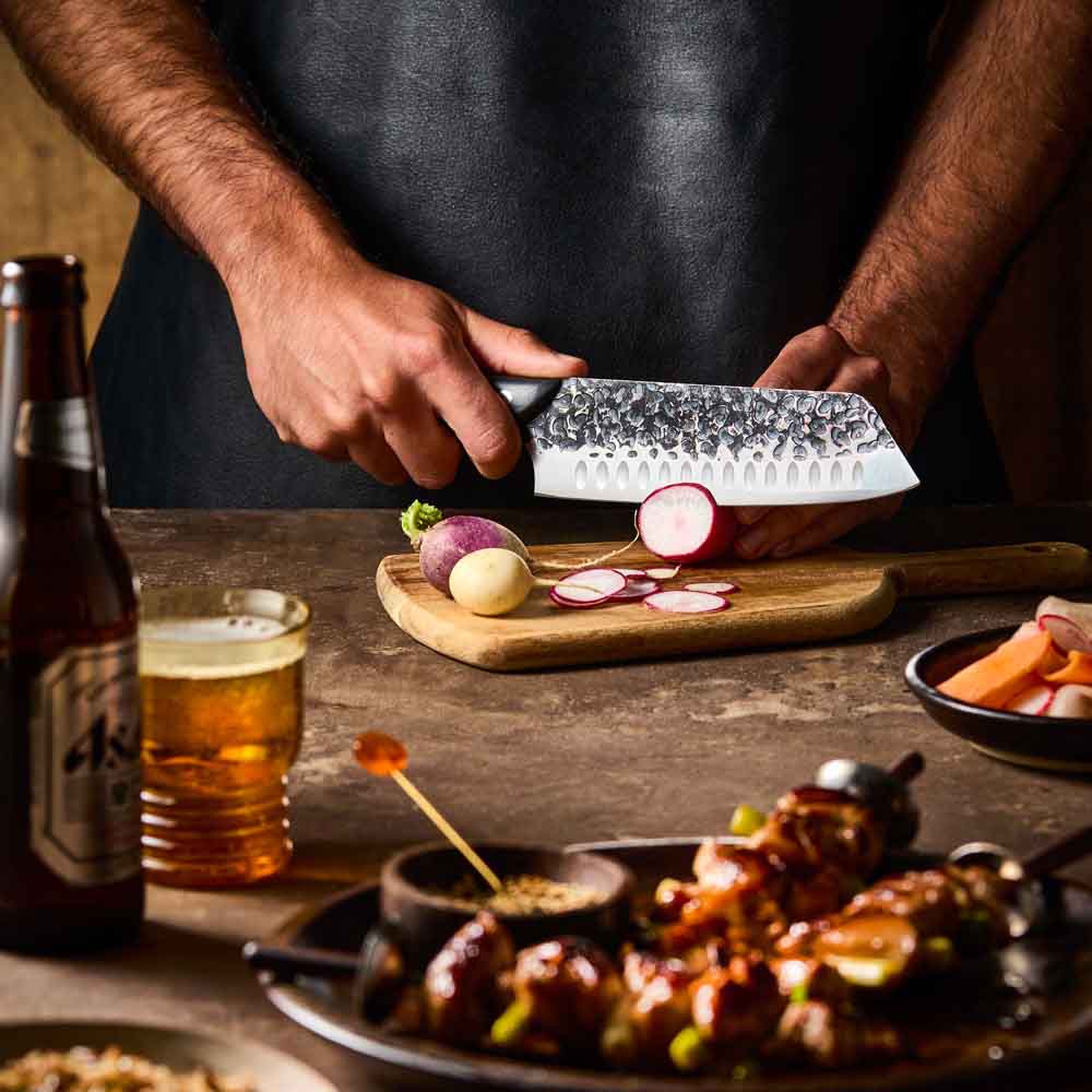 Man slicing radish with Baccarat KUROI KIBA Santoku Knife 18cm at Robins Kitchen