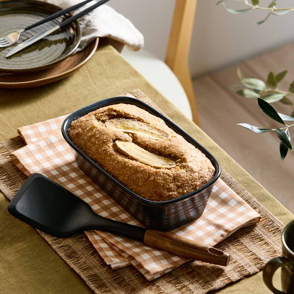 banana bread loaf in a navy blue loaf pan on a table with check tea towel _ Robins Kitchen