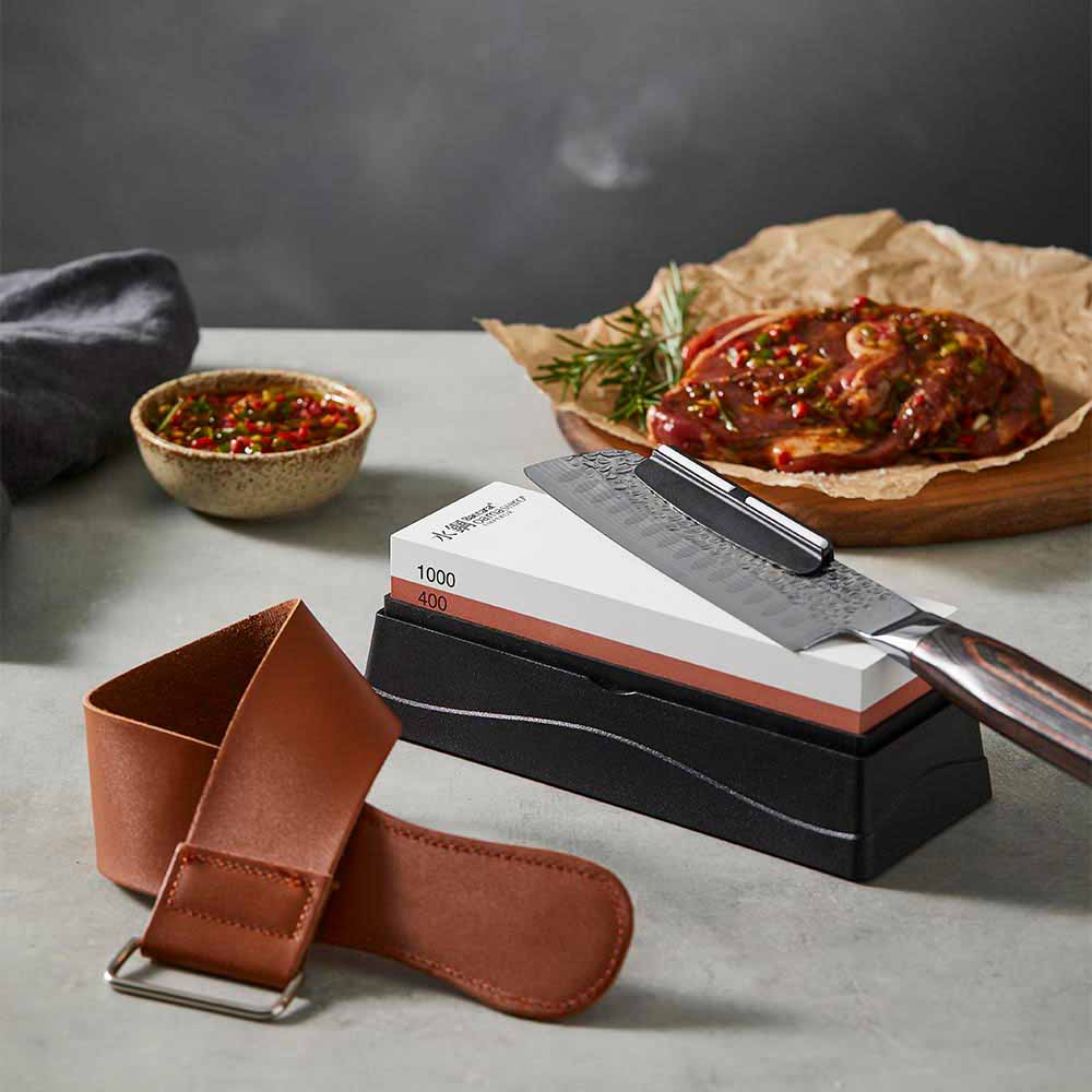 santoku knife sitting on a whetstone with leather strop - Robins Kitchen
