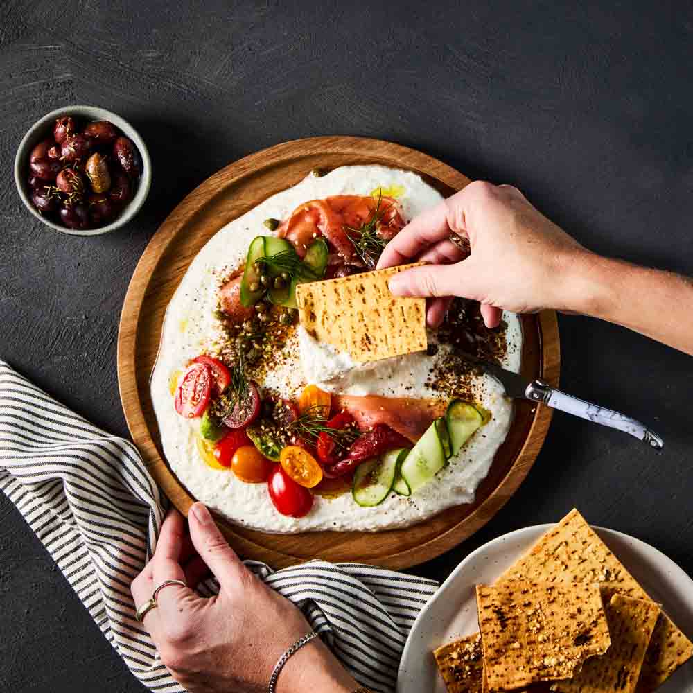 person scooping dip with corn chip from a wooden platter - Robins Kitchen